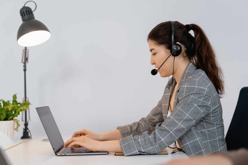 a woman wearing a headset and using a laptop working as a customer support