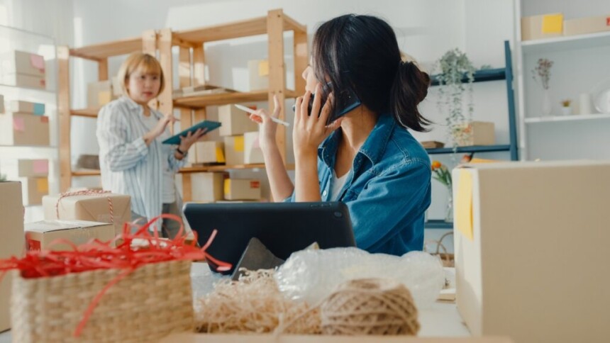 Young Asia businesswomen using mobile phone call receiving purchase order and check product on stock work at home office. Small business owner, online market delivery, lifestyle freelance concept.