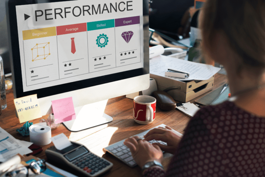 A woman working on a computer displaying the word "performance," focused on managing a remote team.